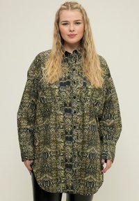 Camicia a maniche lunghe con motivo a stampa di serpente verde e nero, con bottone frontale e una vestibilità oversize, realizzata in un tessuto liscio.