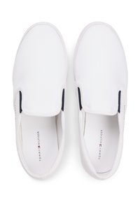 Λευκά παπούτσια χωρίς κορδόνια από καμβά με ναυτικό μπλε ελαστικό πλαϊνό τμήμα και επίπεδη σόλα από καουτσούκ. Διαθέτουν το λογότυπο "TOMMY HILFIGER" τυπωμένο στην εσωτερική σόλα.