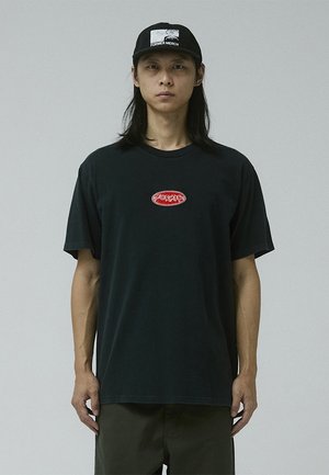 Black cotton t-shirt with short sleeves and a round neckline, featuring a red embroidered logo centered on the chest. Black cap with white logo.