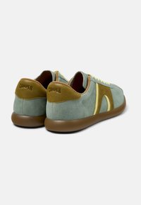 Gröna mockasneakers med gula detaljer, runda bruna gummisulor och framträdande logotyp på baksidan. Snörning.