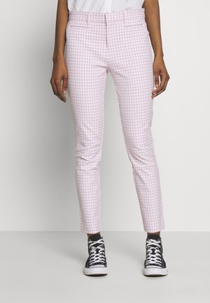 Roze en witte gingham geblokte broek met een aansluitend ontwerp, middelhoge taille en opgerolde enkels, gecombineerd met zwarte high-top sneakers.