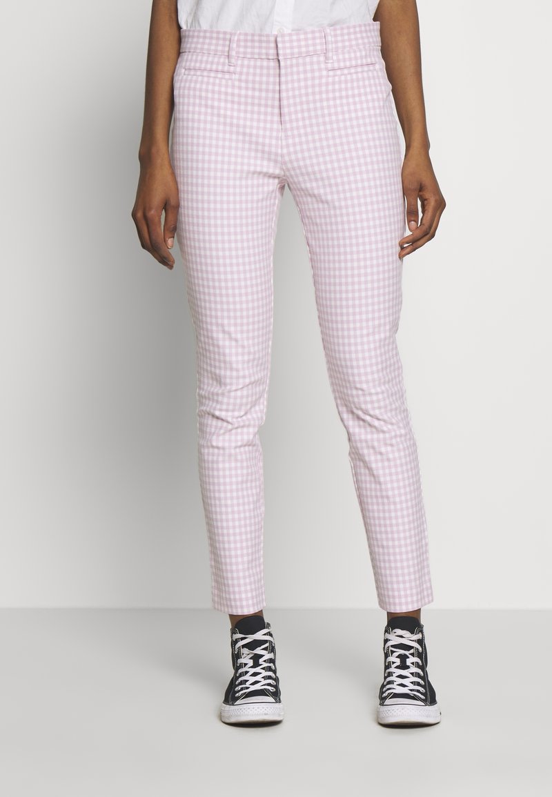 Pantalons à carreaux en vichy rose et blanc avec une coupe ajustée, taille mi-haute et chevilles retroussées, associés à des baskets montantes noires.