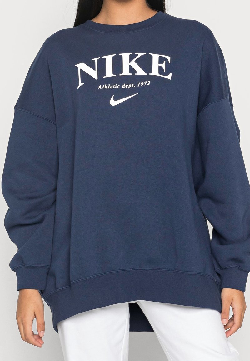 Marinblå Nike sweatshirt med oversized passform, rund halsringning och vit logotext. Mjukt, slätt tyg med ribbade ärmslut och nederkant.