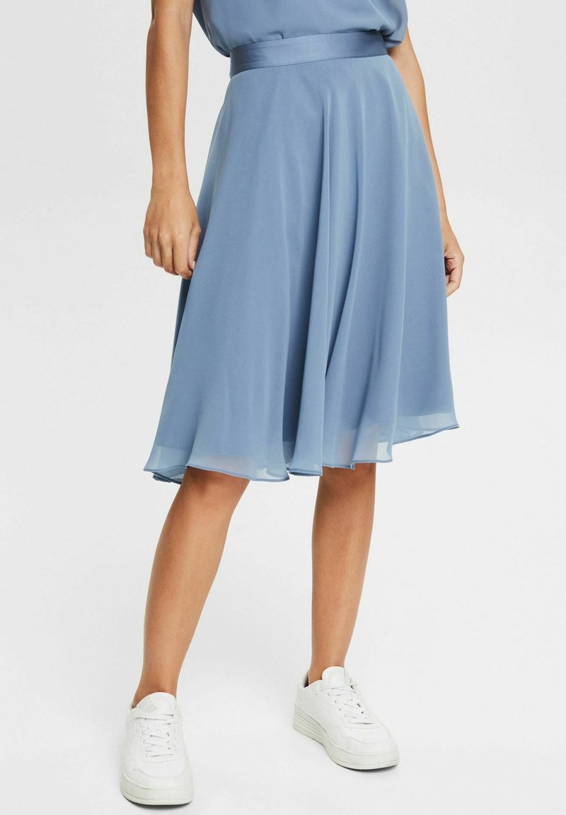 Vaaleansininen polvipituinen hame, joka on valmistettu virtaavasta sifongista. Siinä on muotoiltu vyötärö ja leveä, levenevä malli. Yhdistetty valkoisiin tennareihin.