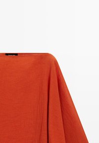 Roestkleurige ponchostijl top met brede boothals en losse, vloeiende mouwen van gestructureerde stof.