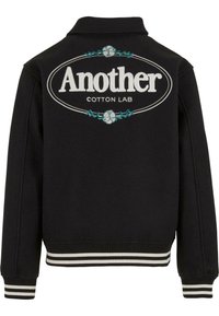 Jachetă neagră dintr-un amestec de bumbac, cu guler tip cămașă. Prezintă text alb brodat "Another" și "COTTON LAB" pe spate, accentuat cu frunze de culoare teal.