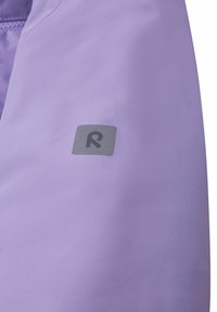 Fioletowy materiał kurtki o gładkiej teksturze. Na rękawie znajduje się kwadratowe logo z stylizowanym „R” w kolorze szarym. Wodoszczelny design.