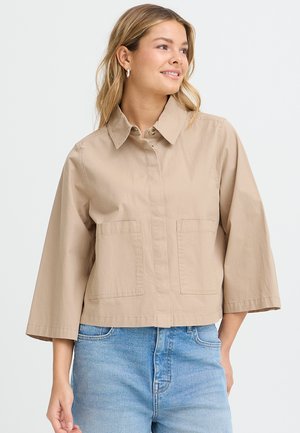 Helebeežist beežikat kropsuuti puuvillasegust jakk, millel on terava krae, kaks esimest taskut ja laiad kolmeveerand varrukad.