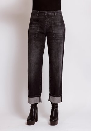 Black cuffed straight-leg jeans paired with black high-heeled platform ankle boots against a plain light background.