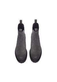 Botas Chelsea de ante gris con paneles laterales elásticos, tiradores y suelas de goma negra. Textura suave y diseño de punta redondeada.