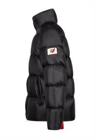Giacca imbottita nera con collo alto, texture trapuntata e patch logo sul braccio superiore. Tasca laterale con zip e accento rosso nella parte inferiore.