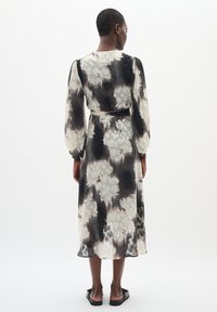 Rochie midi cu model floral, din țesătură transparentă, cu plissuri, cu mâneci lungi și curea la talie. Paletă de culori alb-negru.