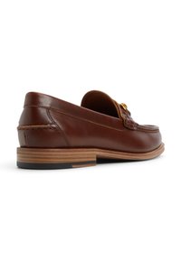 Mocassin en cuir marron à finition lisse, doté d'un ornement en métal doré et d'un petit talon empilé avec une bande en bois contrastante.