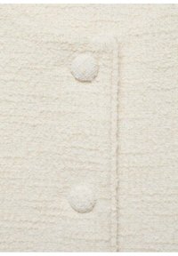 Weißer strukturierter Stoff mit einem erhabenen, gewebten Muster und runden, gewebten Knöpfen auf der Vorderseite. Eine Nahaufnahme hebt die Materialdetails hervor.