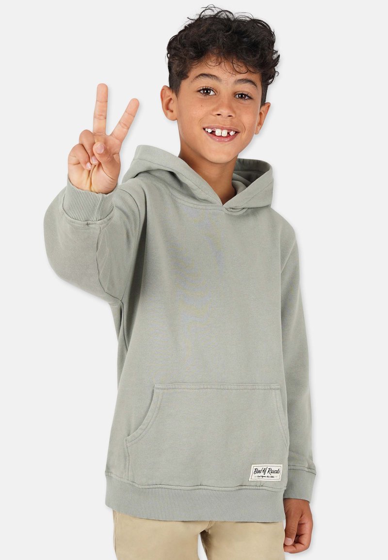 Ljusgrön hoodie i mjukt material, med en framficka, ribbade ärmslut och en etikett i nederkant. Ett barn gör tecknet för fred.