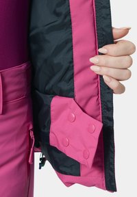Fuchsiaschwarze Jacke mit satinierter Oberfläche, mit schwarzem Futter und pinken Druckknöpfen. Reißverschluss auf der linken Seite, glatte Textur.