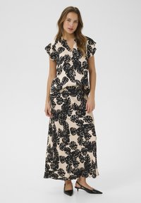 Set di blusa e gonna con motivo a foglia nera su un tessuto crema, caratterizzato da maniche corte, colletto e un design fluido che arriva fino alla caviglia.