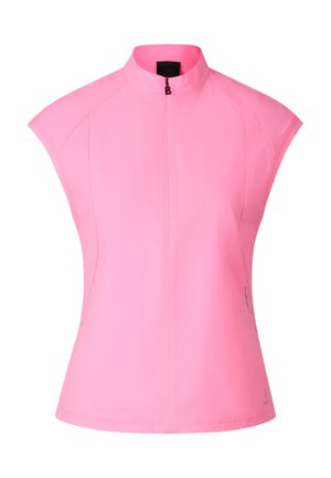 Kobieta ubrana w różowy top bez rękawów na zamek błyskawiczny, czarne spodenki kolarskie, czarne skarpetki i czarne trampki, stojąca na białym tle.