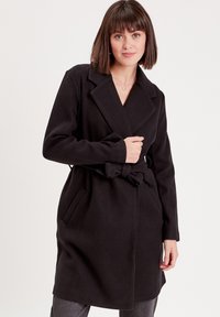 Manteau en laine mélangée noir avec un col châle, une taille ceinturée et deux poches latérales ; texture lisse et design longueur genoux.