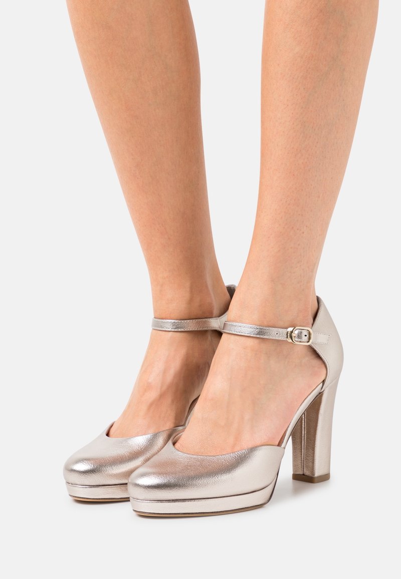 Metalické stříbrné lodičky na vysokém podpatku s zaoblenou špičkou, páskem kolem kotníku s přezkou, platformou a hladkým povrchem.