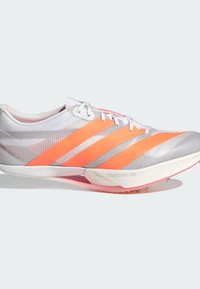 White athletic shoe featuring orange stripes, a streamlined design, textured upper, and a light pink outsole with spike hardware.