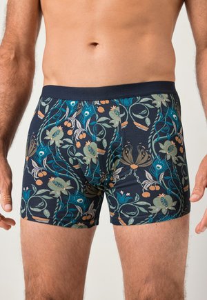 Boxer aderenti da uomo con motivo floreale e botanico colorato su sfondo scuro.