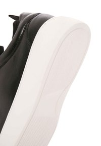 Sneaker in pelle nera con suola in gomma bianca caratterizzata da una texture antiscivolo e una finitura liscia sulla parte superiore. Include una linguetta sul tallone.