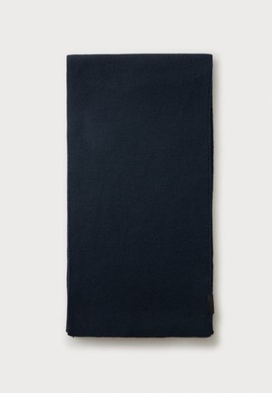 Gefalteter dunkelmarineblauer gestrickter Schal auf einem schlichten hellen Hintergrund mit einem kleinen schwarzen Etikett am Rand.