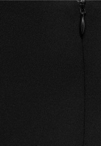 Tissu noir à texture lisse, avec une fermeture éclair en haut et une ligne de couture visible sur le côté gauche.