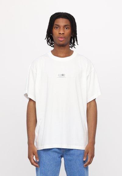 T-shirt en coton blanc à manches courtes et col rond. Présente un motif graphique rectangulaire noir sur la poitrine. Coupe standard.
