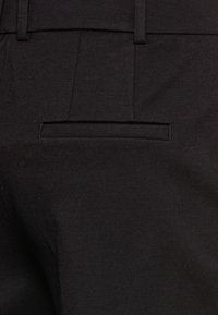 Zwarte tailored broek van een gladde stof met een enkele achterzak met een nette, gestikte afwerking en riemlussen.