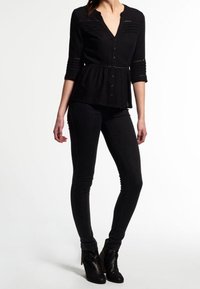 Chemisier noir avec taille peplum, manches trois-quarts et un subtil détail texturé. Associé à un jean skinny noir et des bottines.
