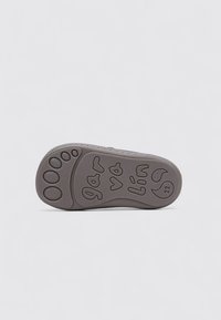 Suela de zapato gris con diseño texturizado de huellas de patas, texto en relieve y agujeros de ventilación. El material parece de caucho con contornos flexibles.