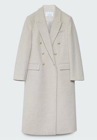 Manteau beige à double boutonnage avec épaulettes, revers crantés, boutons dorés, deux poches avant et une coupe mi-longue.