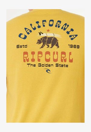 T-shirt en coton jaune avec un imprimé graphique représentant un ours, des planches de surf, ainsi que les textes "California" et "Ripcurl" en couleurs contrastées.