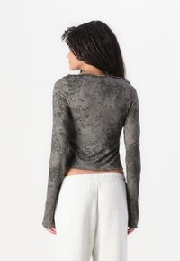 Langemouwige cropped top van gestructureerd donkergrijs stof met een subtiel patroon, met een ronde halslijn en aansluitende mouwen.