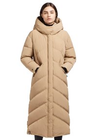 Manteau long beige en duvet avec capuche, présentant un motif en chevron, des poches latérales et une fermeture à glissière. Tissu texturé avec une finition douce.