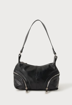 Sac à épaule en cuir noir avec deux fermetures éclair argentées diagonales à l'avant et une seule bandoulière large.