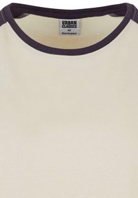 Cremefarvet T-shirt med en mørk lilla ribbet halsudskæring og kontrastkanter, forsynet med et mærke, der hedder "Urban Classics." Blødt bomuldsstof.
