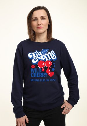 Marineblå sweatshirt med grafisk tryk af røde kirsebær, teksten "Prøv en vild kirsebær" og detaljer i blå og rød. 100% bomuldsstof, rund hals.