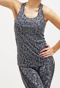 Débardeur de sport noir et gris à motifs avec une encolure arrondie, assorti à un legging avec des rayures ondulées. Tissu extensible et ajusté.
