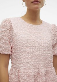Rosa texturerad klänning med volangtyg, korta puffärmar och rund halsringning med en samlad midja.