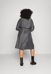 Grå skjortklänning med bälte, lång ärm, krage och längd till halva vaden. Har en mjuk textur och stiliga sömdetaljer.