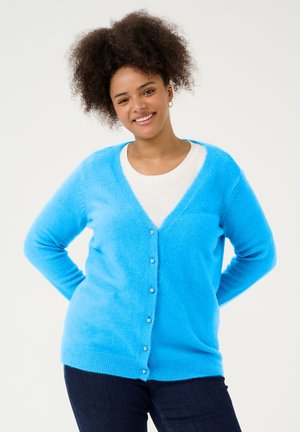 Light blue knitted cardigan with a V-neck, long sleeves, and buttons down the front. Soft texture, relaxed fit, worn over a white top.