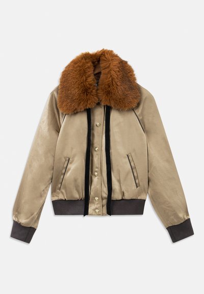 Beige satiin bomber jacket, jossa on ruskea turkiskaulus, musta samettinen etureuna, kultaiset napit sekä ribatoidut hihansuut ja helma.