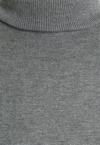 Pulover gri cu guler înalt, textură canelată, material tricotat moale, vedere de aproape care evidențiază gulerul înalt și modelul fin și uniform.