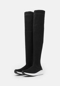 Botas deportivas negras hasta la rodilla con un tejido texturizado y transpirable y suelas blancas. Presentan una puntera de goma y una parte superior de punto ajustada.