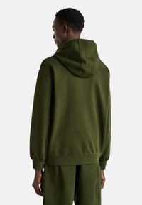 Felpa verde in cotone con un grande cappuccio, polsini a coste e vestibilità rilassata. Texture liscia e cuciture minime. Vista posteriore mostrata.