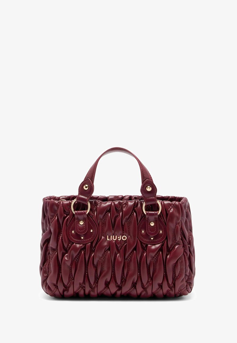 Sac à main matelassé rouge avec une surface texturée, des accents en métal doré, des poignées doubles et une plaque logo. Design compact et structuré.