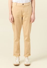 Beiga byxor i bomull med rak bendesign, uppvikt fåll och knappstängning. Matchas med vita och beiga sneakers.
